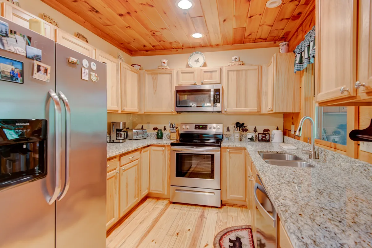 A close-up of the cabin’s kitchen, featuring stainless steel appliances, granite countertops, and rich wooden cabinetry. The space feels modern yet warm, suggesting a well-stocked and functional kitchen for meal prep and family bonding.