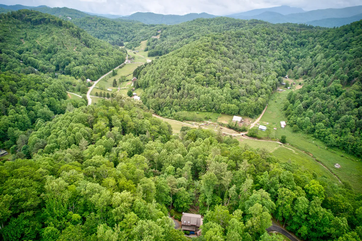This scenic view captures lush green forests, winding roads, distant mountains, and scattered houses. It evokes the broader region’s natural beauty and the promise of exploration in the surrounding landscape—a perfect visual for local outings and mountain adventures.